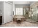Bright bathroom featuring a glass-enclosed shower, soaking tub, neutral tile, and shuttered window at 9865 E Piedra Dr, Scottsdale, AZ 85255