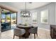 A breakfast nook featuring a modern chandelier, three windows with white shutters, and a view to the outdoor patio at 9865 E Piedra Dr, Scottsdale, AZ 85255
