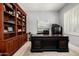 Well-lit home office featuring custom built-in wood shelving, large desk, and neutral color palette at 9865 E Piedra Dr, Scottsdale, AZ 85255