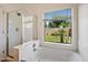 Bright bathroom area featuring a soaking tub, separate glass shower and green outdoor view at 10152 E Knowles Ave, Mesa, AZ 85209