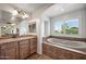 Well-lit bathroom featuring a soaking tub, vanity, and decorative lighting fixtures at 11785 N 143Rd Dr, Surprise, AZ 85379