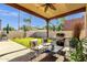 Covered outdoor patio with seating, grill, and views of the spacious backyard and swaying palm trees at 1554 E Kings Ct, Gilbert, AZ 85234