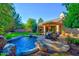 Inviting backyard featuring a sparkling pool with a rock waterfall and a patio with an umbrella table set at 1681 S Karen Dr, Chandler, AZ 85286