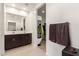 Bright bathroom features a double sink vanity, framed mirror, and doorway to walk-in closet at 17344 W Red Fox Rd, Surprise, AZ 85387