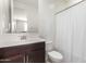 Neutral bathroom features a vanity, toilet, and a shower with a white curtain at 17344 W Red Fox Rd, Surprise, AZ 85387