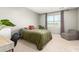 Cozy bedroom featuring soft carpet, a window with curtains, and a comfortable bed with a plant at 17344 W Red Fox Rd, Surprise, AZ 85387