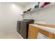 Laundry room features a washer, dryer, and wall-mounted shelves for ample storage at 17344 W Red Fox Rd, Surprise, AZ 85387