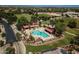 Aerial view of a community pool area featuring two pools, lounge chairs, and covered seating areas amidst a lush green landscape at 19042 E Arrowhead Trl, Queen Creek, AZ 85142