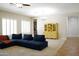Open-concept living room featuring a blue sectional sofa, a yellow hutch, and plantation shutters at 20243 E Poco Calle --, Queen Creek, AZ 85142