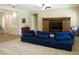 Bright living room featuring a plush blue sofa, a wooden media center, and large windows with plantation shutters at 20243 E Poco Calle --, Queen Creek, AZ 85142