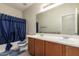 Bathroom with a double sink vanity, tile accents, framed mirror, and bathtub with blue curtain at 29399 N 67Th Ave, Peoria, AZ 85383