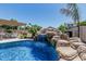 Stunning pool with a natural rock waterfall and lush tropical landscaping, creating a serene and private retreat at 3067 E Trigger Way, Gilbert, AZ 85297
