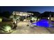Nighttime view of a sparkling pool with a waterfall, surrounded by lush landscaping and a cozy outdoor living area at 3067 E Trigger Way, Gilbert, AZ 85297