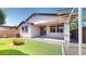 Backyard with artificial grass, covered patio, mature trees, and low-maintenance rock landscaping at 3877 E Oxford Ln, Gilbert, AZ 85295