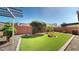 Well-maintained backyard featuring artificial grass, rock landscaping, and mature plants for serene enjoyment at 3877 E Oxford Ln, Gilbert, AZ 85295