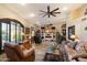 Cozy living room with a brick fireplace, a ceiling fan, and large windows with wood shutters at 401 N Cholla St, Chandler, AZ 85224