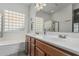 Bright bathroom with glass block window, walk-in shower, and dual sinks with wood cabinets at 4396 N School Hill Rd, Buckeye, AZ 85396