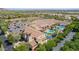 Aerial view of a community pool and clubhouse surrounded by palm trees, parking area, and lush greenery at 4396 N School Hill Rd, Buckeye, AZ 85396