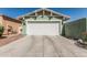 Frontal view of a two-car garage with a white door and a wide driveway, complemented by desert landscaping at 4396 N School Hill Rd, Buckeye, AZ 85396