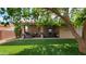 Charming covered patio with outdoor seating overlooks a beautiful backyard with artificial turf and mature trees at 650 N 65Th Way, Mesa, AZ 85205