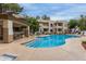 Gorgeous community swimming pool with several chairs in front of the condo complex under a partly cloudy sky at 750 E Northern E Ave # 2145, Phoenix, AZ 85020