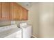 Bright laundry room with side-by-side white washer and dryer, and wooden cabinets overhead at 9302 E Horseshoe Bend Dr, Scottsdale, AZ 85255