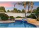 Sparkling pool featuring a waterfall, surrounded by lush landscaping and palm trees, creating a tropical oasis at 1001 N Peppertree Dr, Gilbert, AZ 85234