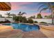 Beautiful pool with stone patio and palm trees against a vibrant sunset sky at 1001 N Peppertree Dr, Gilbert, AZ 85234