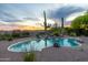 Inviting pool area featuring desert landscaping and a small waterfall under a beautiful colorful dusk sky at 10875 E Mirasol Cir, Scottsdale, AZ 85255
