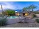 Inviting pool area with lounge chairs, solar panels on roof, and verdant desert landscaping at dusk at 10875 E Mirasol Cir, Scottsdale, AZ 85255
