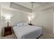Comfortable bedroom with a ceiling fan, tray ceiling, and side tables with lamps on either side of the bed at 13805 N Hamilton Dr # H102, Fountain Hills, AZ 85268