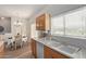 Sunlit kitchen features a dining area, wooden cabinets, white countertops, and stainless steel sink under a window at 13805 N Hamilton Dr # H102, Fountain Hills, AZ 85268