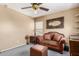 Comfortable living room with a plush brown couch, soft gray carpet, and decorative mirror at 22022 W Moonlight Path, Buckeye, AZ 85326