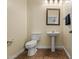 Cozy half-bathroom, complete with pedestal sink, wooden mirror frame, and warm-toned tile floor, creates a welcoming space at 2592 E San Rafael Trl, Casa Grande, AZ 85194