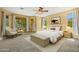 Bright bedroom with large windows, ceiling fan, neutral carpet, and upholstered bench at end of bed at 2592 E San Rafael Trl, Casa Grande, AZ 85194