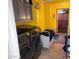 Laundry room with gray cabinets, yellow walls, and stainless steel washer and dryer at 3060 E Hope St, Mesa, AZ 85213
