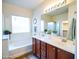 Well-lit bathroom with double sinks, a soaking tub, and modern fixtures at 35721 N Zachary Rd, Queen Creek, AZ 85144