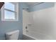 Bathroom with a white bathtub with shower, white tiling, toilet and a bright window at 36114 W Vera Cruz Dr, Maricopa, AZ 85138