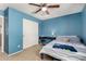 Bedroom with blue walls, a ceiling fan, a bed, a desk, and closet doors at 36114 W Vera Cruz Dr, Maricopa, AZ 85138