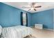 Bedroom features blue walls, ceiling fan, window, and modern decor at 36114 W Vera Cruz Dr, Maricopa, AZ 85138