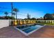 Backyard pool with spa is bordered by manicured hedges and palm trees under a twilight sky at 4107 E Edgemont Ave, Phoenix, AZ 85008