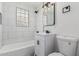 A clean bathroom featuring an elegant vanity, glass block window, and a shower/tub combo at 4531 N 12Th Dr, Phoenix, AZ 85013