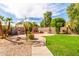 Lush backyard featuring a fireplace, manicured lawn, desert landscaping, and a paved pathway at 492 E Vermont Dr, Gilbert, AZ 85295