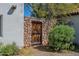 Rustic outdoor entrance with a wooden gate, a stone wall, and vibrant green foliage at 6418 E Sunnyside Dr, Scottsdale, AZ 85254