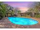 Gorgeous pool and backyard at dusk, framed by mature trees and leading to a charming covered outdoor space at 6418 E Sunnyside Dr, Scottsdale, AZ 85254
