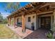Inviting covered porch with exposed wood beams, brick flooring, and a cozy seating area at 6418 E Sunnyside Dr, Scottsdale, AZ 85254