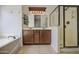 Bathroom featuring a double vanity, soaking tub, and glass-enclosed shower at 6941 E Snowdon St, Mesa, AZ 85207
