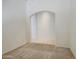 Open living space with neutral carpet leading to an arched doorway and tile flooring at 6941 E Snowdon St, Mesa, AZ 85207