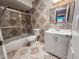 Well-lit bathroom with tiled floors, a modern vanity, and a shower-tub combo with glass doors at 7903 N 61St Ave, Glendale, AZ 85301