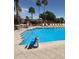 Inviting community pool featuring accessible chairlift, stone accents, and lounge chairs under palm trees at 8865 E Baseline Rd # 614, Mesa, AZ 85209